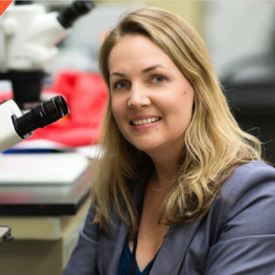 Tajie H. Harris headshot posed next to a microscope
