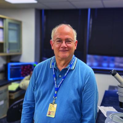 Scott Zeitlin photographed in lab environment with blue shirt and lanyard